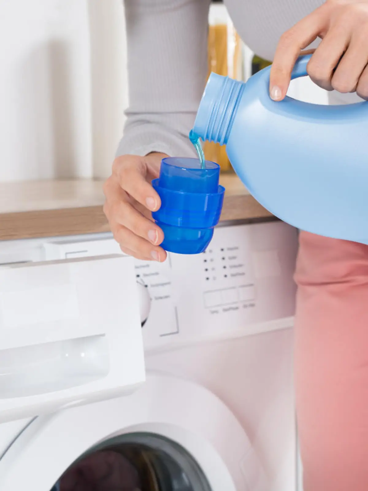 Close-up Of Female Hands Pouring Detergent In The Blue Bottle Cap