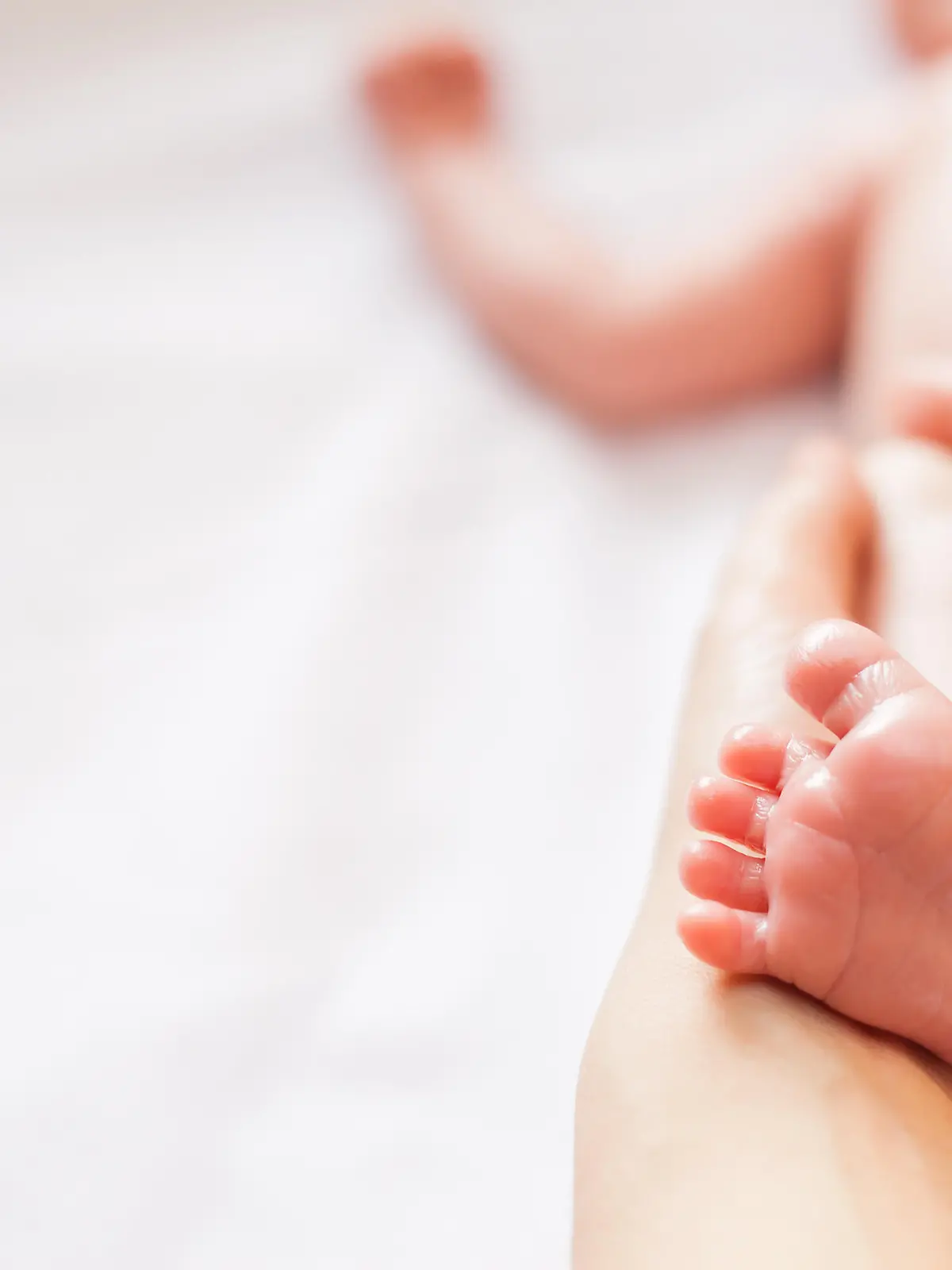 Mother makes massage for happy baby, apply oil on the foot, with white background