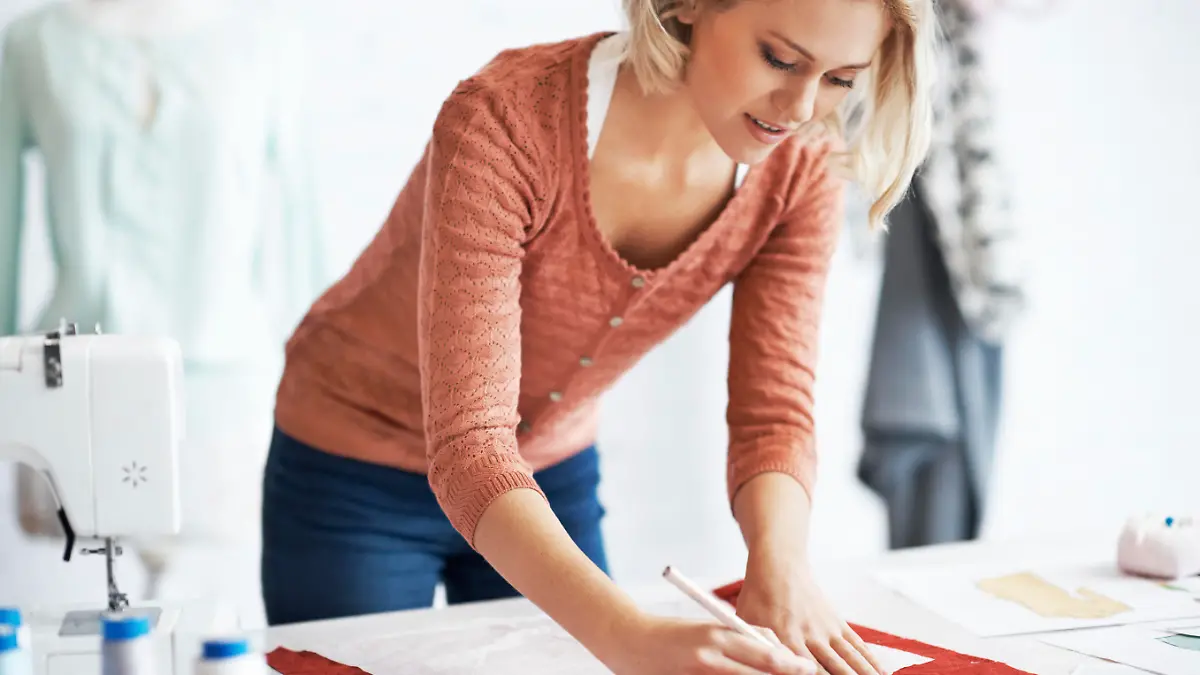 A beautiful young tailor drawing the outline of a pattern for a garment
