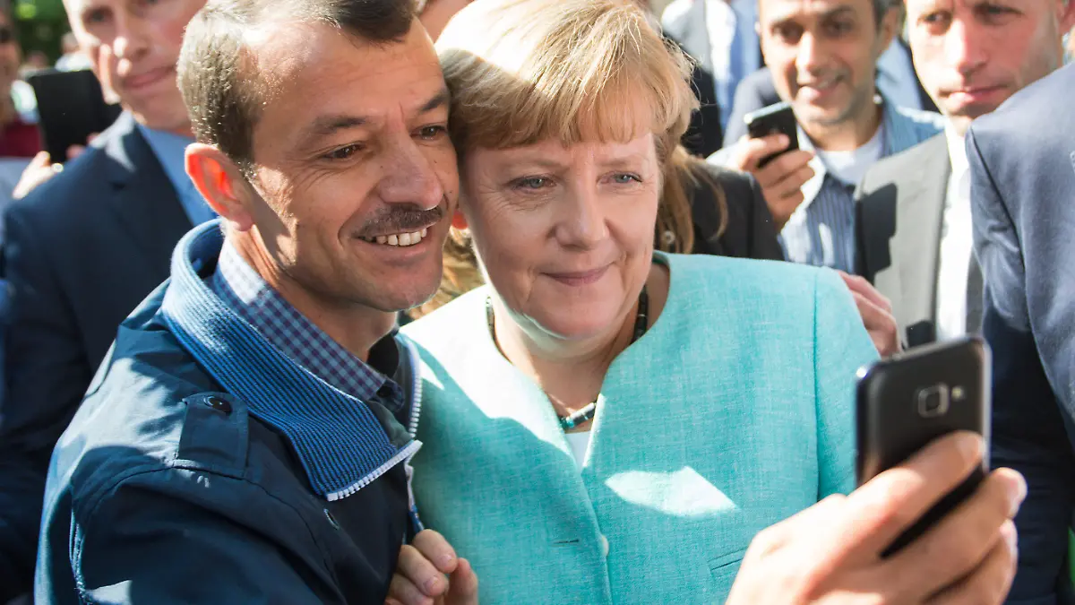 ARCHIV - Bundeskanzlerin Angela Merkel (CDU) lässt sich am 10.09.2015 nach dem Besuch einer Erstaufnahmeeinrichtung für Asylbewerber der Arbeiterwohlfahrt (AWO) und der Außenstelle des Bundesamtes für Migration und Flüchtlinge in Berlin-Spandau für ein Selfie zusammen mit einem Flüchtling fotografieren. Foto: Bernd von Jutrczenka/dpa (zu dpa «Zwischen Reem und Seehofer - Merkels Weg zur Flüchtlingskanzlerin») +++(c) dpa - Bildfunk+++