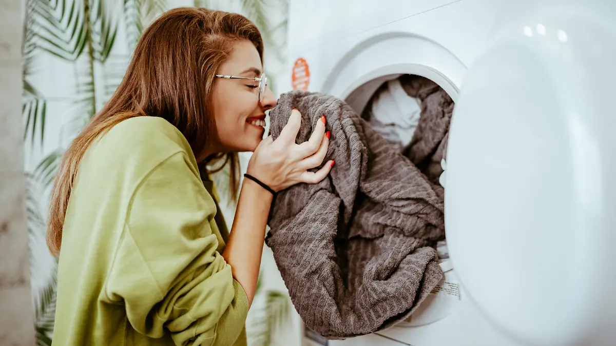 Young woman takes laundry out of the washing machine