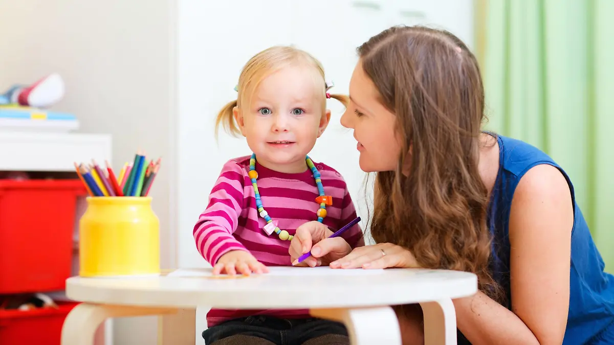junge Mutter sitzt zusammen mit ihrer kleinen Tochter am Tisch und malt | young mother sitting at the table with her little daughter drawing together