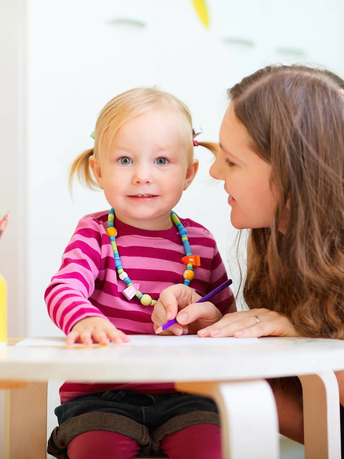 junge Mutter sitzt zusammen mit ihrer kleinen Tochter am Tisch und malt | young mother sitting at the table with her little daughter drawing together