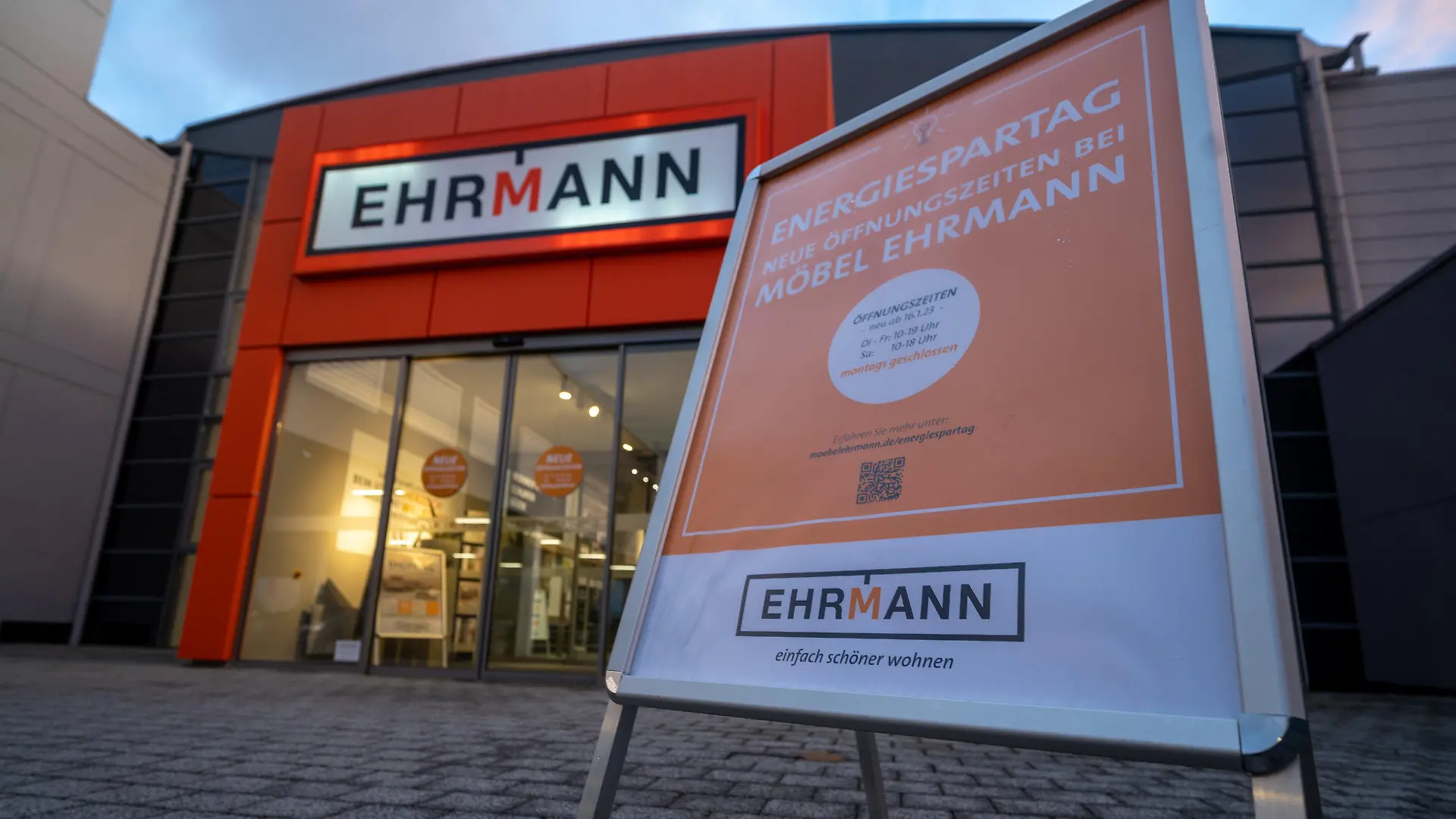 11.01.2023, Rheinland-Pfalz, Trier: Ein Aufsteller, der darauf hinweist, dass die Verkaufsräume montags geschlossen sind, steht am Eingang des Möbelhauses Ehrmann in Trier. Grund sind die gestiegenen Energiekosten. Foto: Harald Tittel/dpa +++ dpa-Bildfunk +++