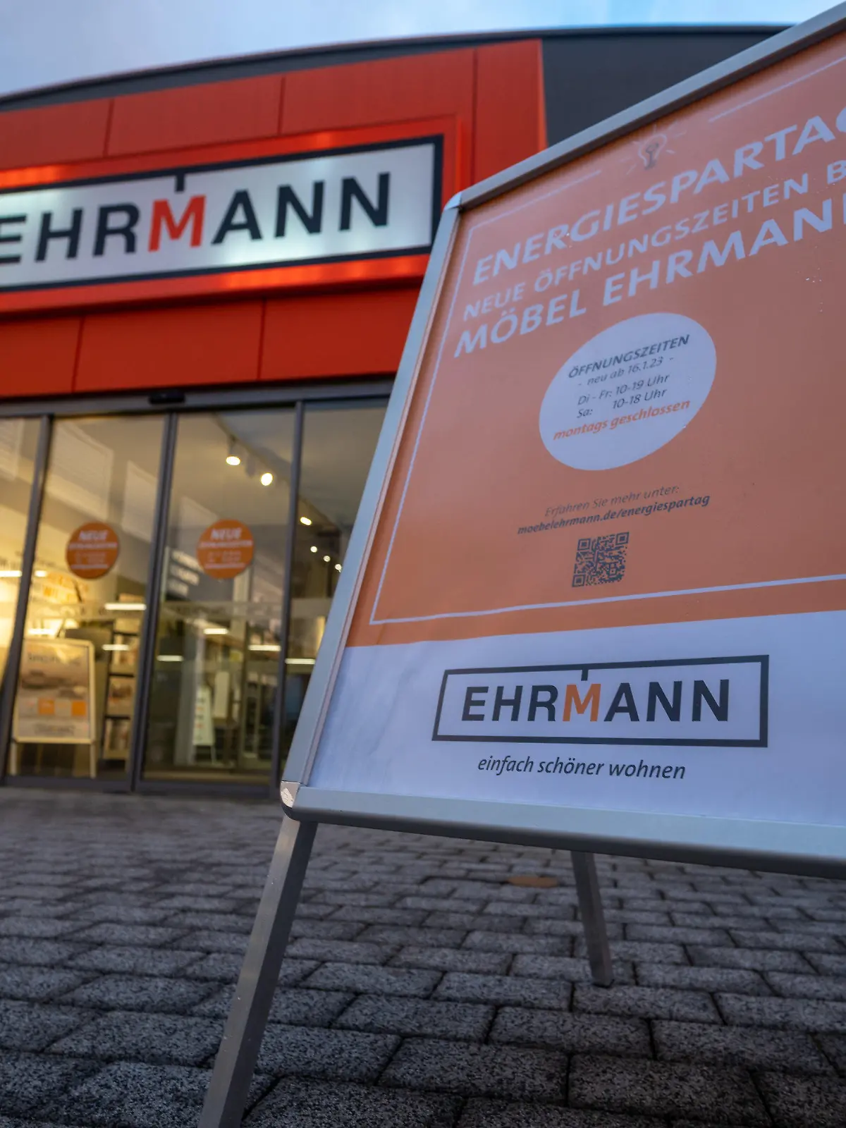 11.01.2023, Rheinland-Pfalz, Trier: Ein Aufsteller, der darauf hinweist, dass die Verkaufsräume montags geschlossen sind, steht am Eingang des Möbelhauses Ehrmann in Trier. Grund sind die gestiegenen Energiekosten. Foto: Harald Tittel/dpa +++ dpa-Bildfunk +++