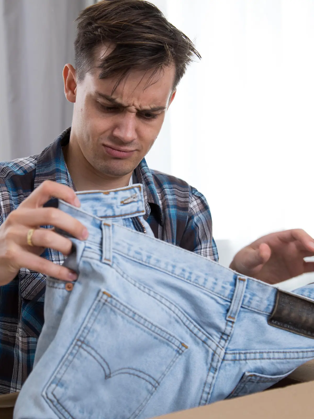 ILLUSTRATION - Ein junger Mann oeffnet am 14.09.2018 in Hamburg ein Paket und nimmt eine Jeans raus (gestellte Szene). Foto: Christin Klose