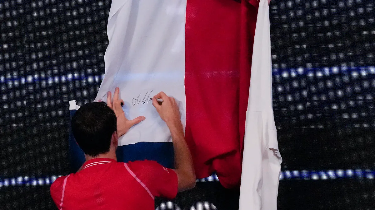 Daniil Medvedev of Russia autographs a Russian flag after defeating Marcos Giron of the U.S. in their first round match at the Australian Open tennis championship in Melbourne, Australia, Monday, Jan. 16, 2023. (AP Photo/Aaron Favila)