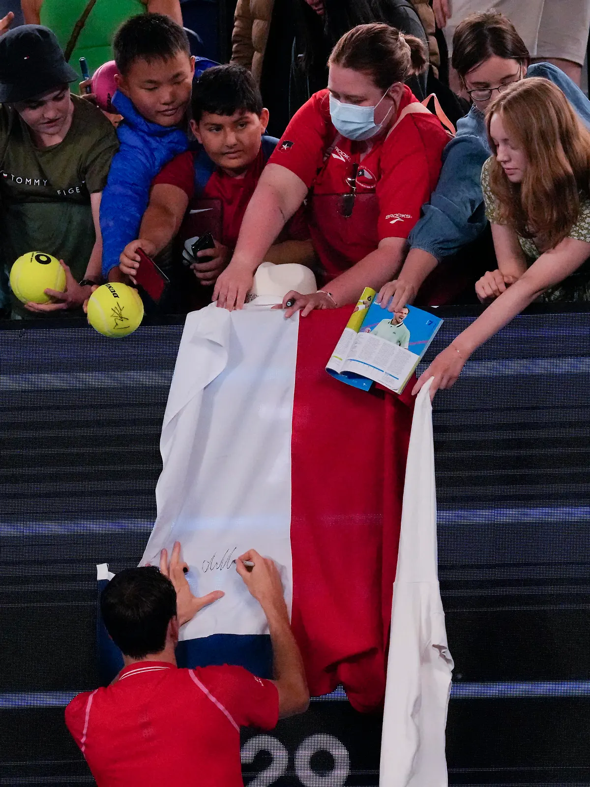 Daniil Medvedev of Russia autographs a Russian flag after defeating Marcos Giron of the U.S. in their first round match at the Australian Open tennis championship in Melbourne, Australia, Monday, Jan. 16, 2023. (AP Photo/Aaron Favila)