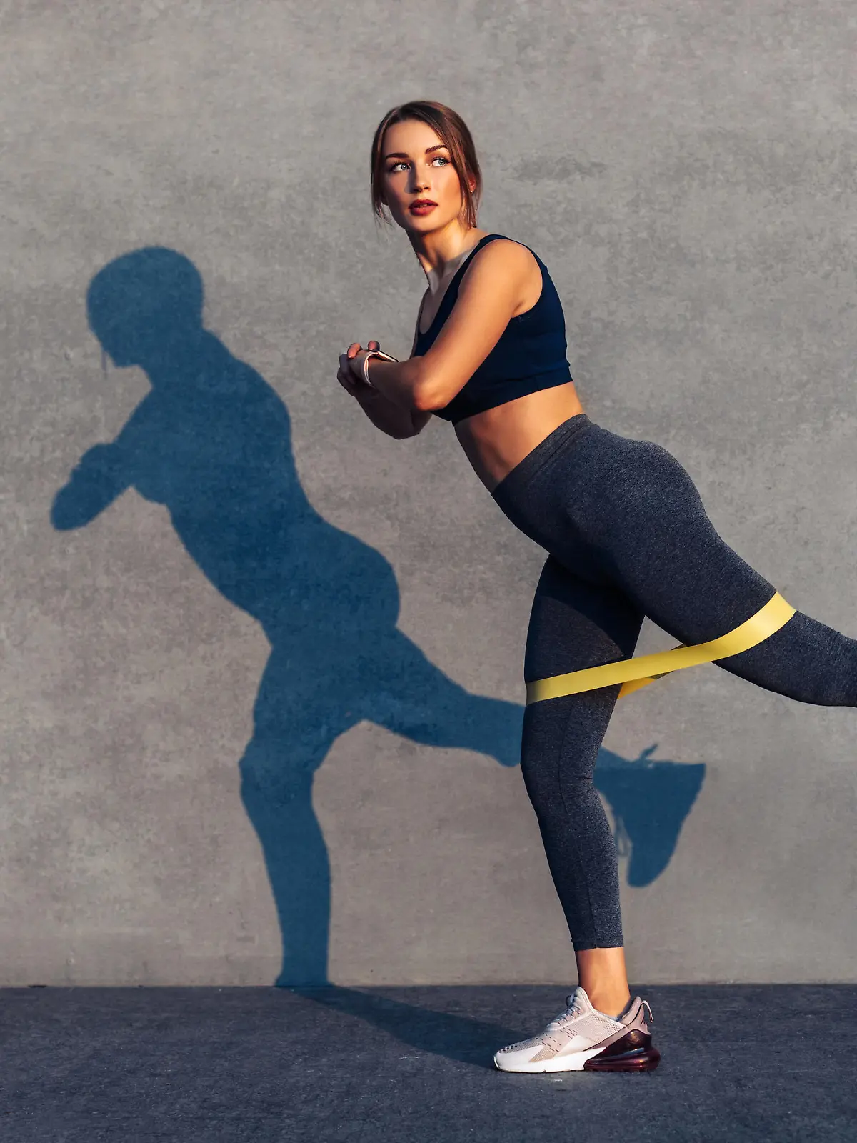 Beautiful sportive woman doing exercises with a resistance band, an athlete with a work band with an elastic band outdoors, Young woman performing fitness exercises on the street