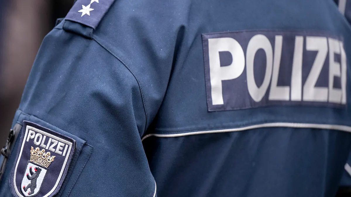 ARCHIV - 05.12.2022, Berlin: Die Aufschrift Polizei und der Wappen von Berlin auf der Uniform eines Polizeibeamten, aufgenommen bei einem Pressetermin zur Ausweitung des Einsatzes von Bodycams bei Polizei und Feuerwehr. (zu dpa «101 Ermittlungen wegen problematischer Gruppen-Chats von Polizisten») Foto: Monika Skolimowska/dpa +++ dpa-Bildfunk +++