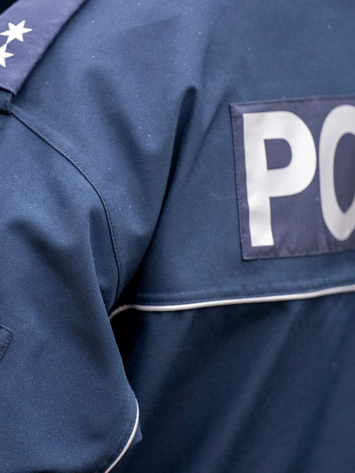 ARCHIV - 05.12.2022, Berlin: Die Aufschrift Polizei und der Wappen von Berlin auf der Uniform eines Polizeibeamten, aufgenommen bei einem Pressetermin zur Ausweitung des Einsatzes von Bodycams bei Polizei und Feuerwehr. (zu dpa «101 Ermittlungen wegen problematischer Gruppen-Chats von Polizisten») Foto: Monika Skolimowska/dpa +++ dpa-Bildfunk +++