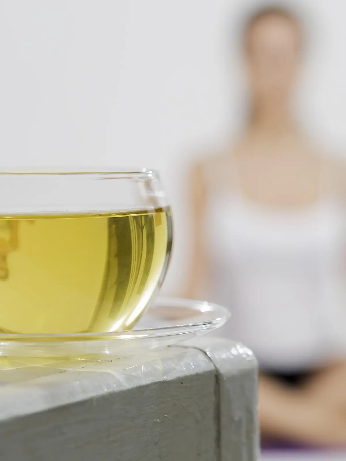 ILLUSTRATION - Eine junge Frau im Meditationssitz spiegelt sich am 16.03.2015 in einem Studio in Berlin in einer Tasse Tee. Foto: Monique Wuestenhagen | Verwendung weltweit