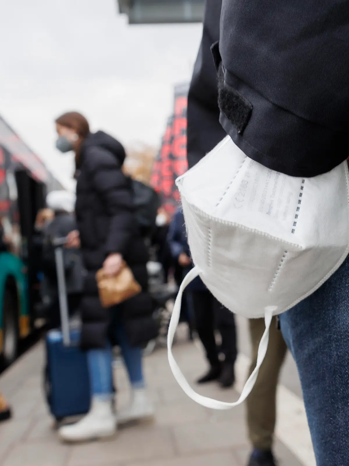 05.12.2022, Baden-Württemberg, Stuttgart: Ein Mann wartet mit einer Maske am Handgelenk auf einen Bus am Stuttgarter Hauptbahnhof. Die digitale Gesundheitsministerkonferenz der Länder berät über die Zukunft der Maskenpflicht. Foto: Julian Rettig/dpa +++ dpa-Bildfunk +++