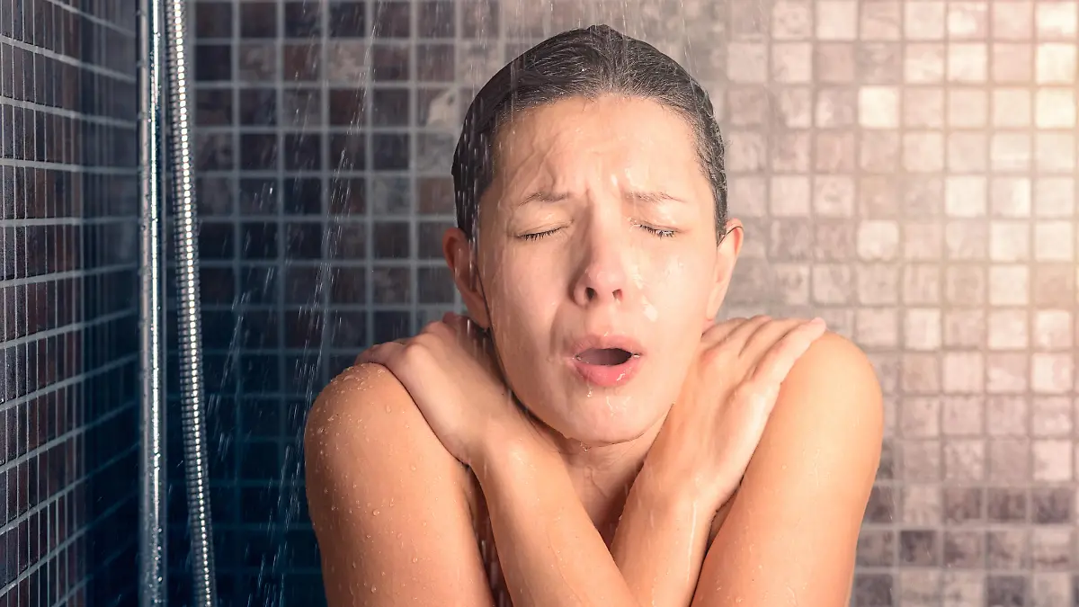 Close up Bare Young Woman Reacting While Taking Cold Shower with Arms Crossing Over her Chest and Eyes Closed.