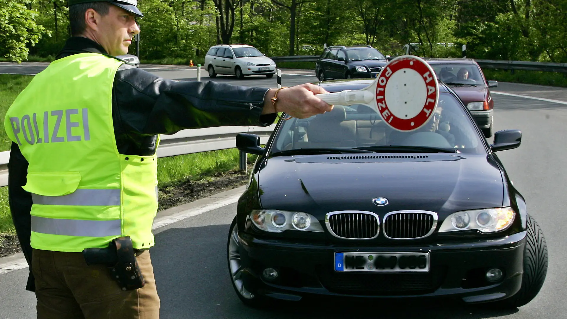 ARCHIV - Mit der Kelle stoppt ein Polizist einen Autofahrer auf der Autobahn 46 Richtung Neuss (Archivfoto vom 28.04.2005) Verkehrsrowdys sollen künftig stärker zur Kasse gebeten werden. «Wer als Rowdy vorsätzlich rast oder drängelt, soll künftig bis zu 2000 Euro zahlen», sagte Bundesverkehrsminister Wolfgang Tiefensee der «Bild»-Zeitung (16.05.2006). Foto: Roland Weihrauch +++(c) dpa - Bildfunk+++