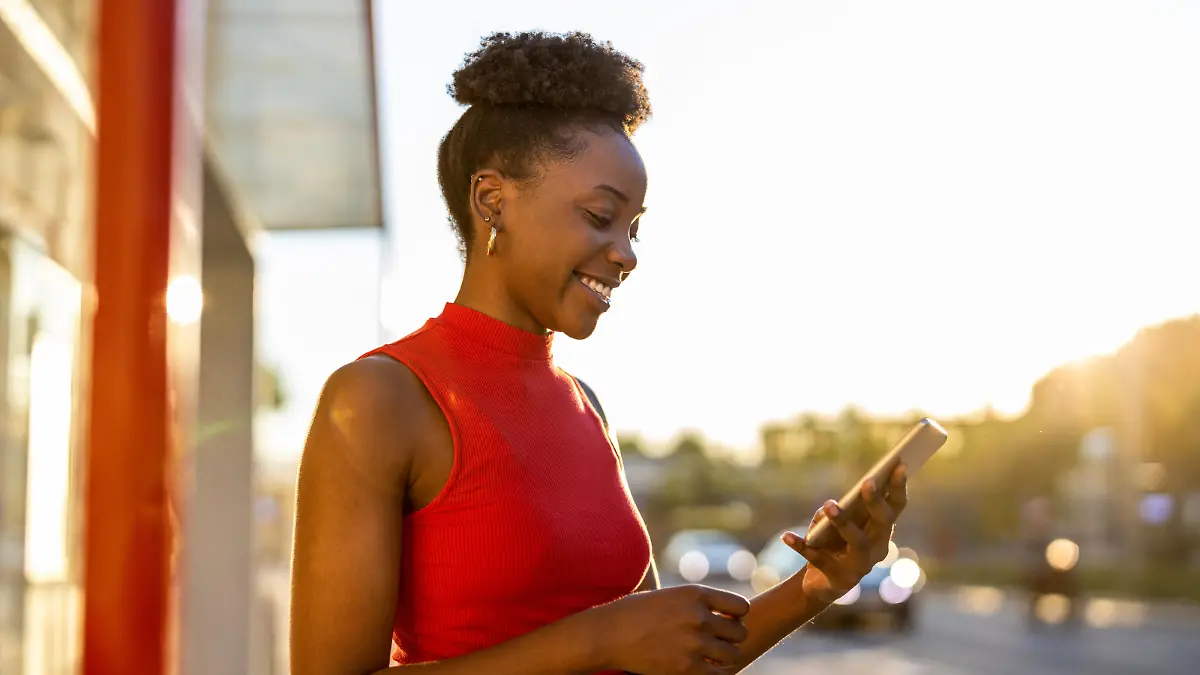 Young woman with smartphone waiting at the bus stop