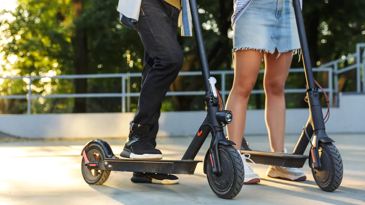 Zwei Menschen auf und neben ihren E-Scootern