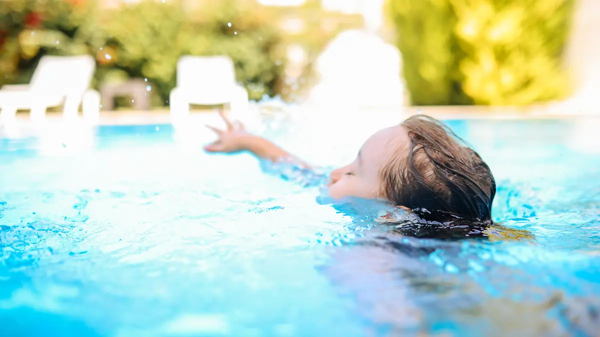 Happy laughing toddler boy having fun in a swimming pool