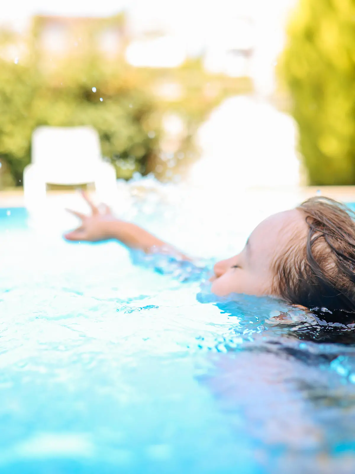 Happy laughing toddler boy having fun in a swimming pool