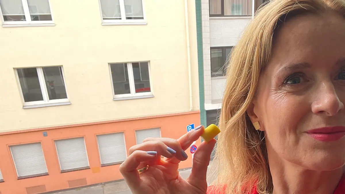 Redakteurin Maren Mangold zeigt 3M Ohrstöpsel neben ihrem Ohr vor einem Fenster Richtung Straße.