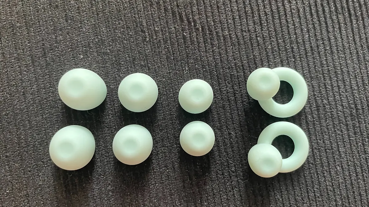 Vier Aufsätze des Loop Ohrstöpsels mit Ring nebeneinander auf einem schwarzen Hocker.