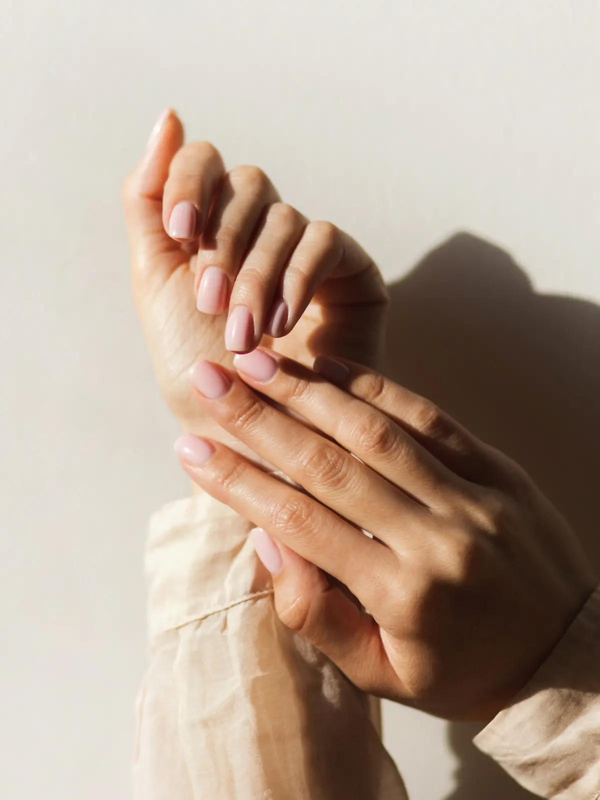 Frau trägt einen Nagellack in einem zarten Rosaton.