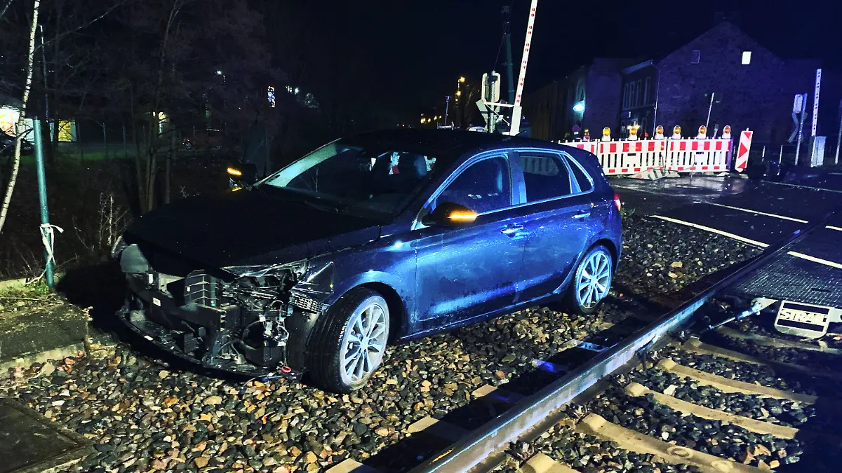HANDOUT - 14.01.2023, Nordrhein-Westfalen, Stolberg: Ein demoliertes Auto steht neben den Schienen. Bei einem Zusammenstoß eines Autos mit einem Zug sind in Stolberg zwei Menschen verletzt worden. Eine Euregiobahn war am Samstagabend an einem Bahnübergang mit dem Pkw zusammengestoßen. Foto: -/ Feuerwehr Stolberg/dpa +++ dpa-Bildfunk +++
