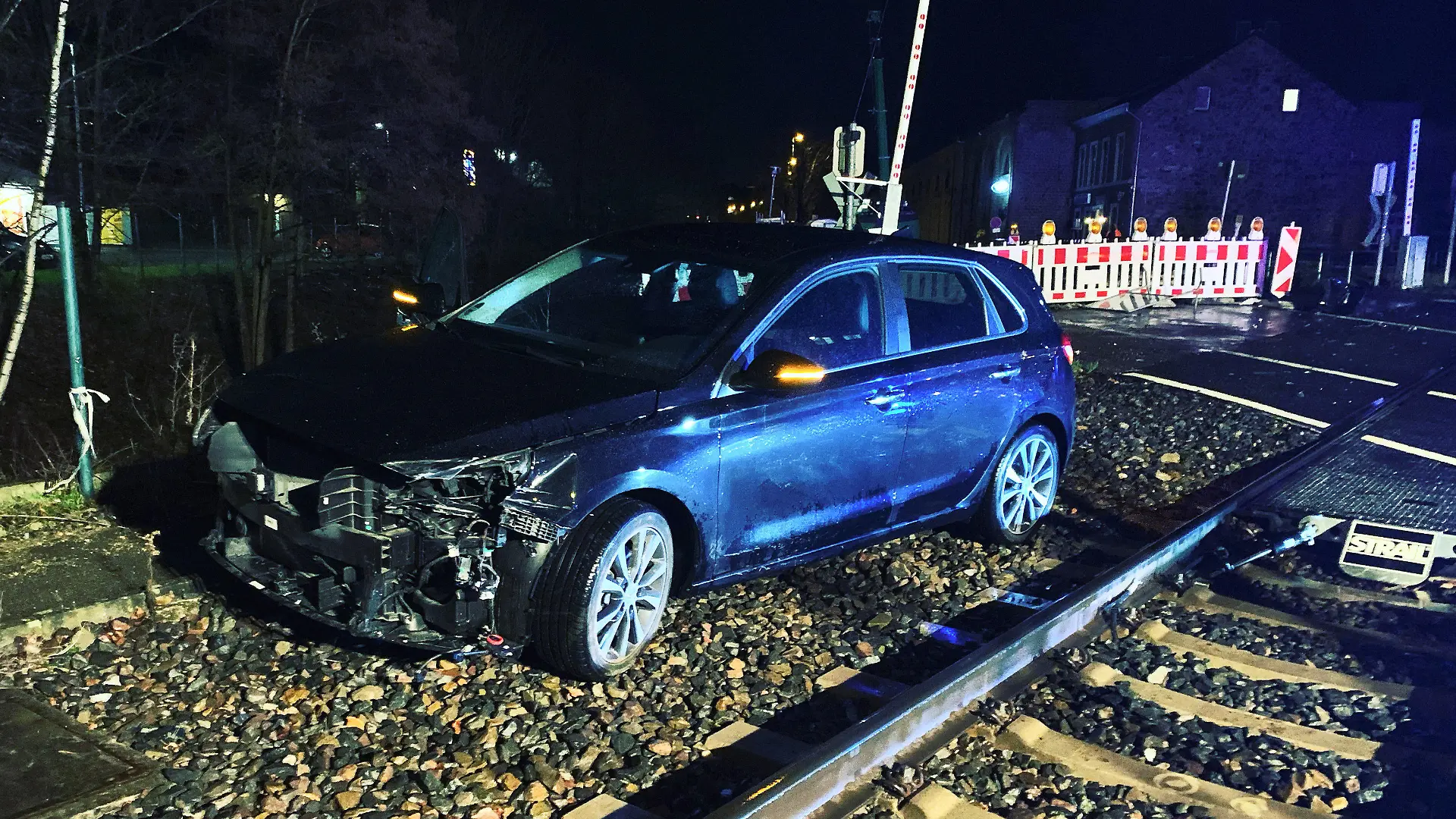 HANDOUT - 14.01.2023, Nordrhein-Westfalen, Stolberg: Ein demoliertes Auto steht neben den Schienen. Bei einem Zusammenstoß eines Autos mit einem Zug sind in Stolberg zwei Menschen verletzt worden. Eine Euregiobahn war am Samstagabend an einem Bahnübergang mit dem Pkw zusammengestoßen. Foto: -/ Feuerwehr Stolberg/dpa +++ dpa-Bildfunk +++