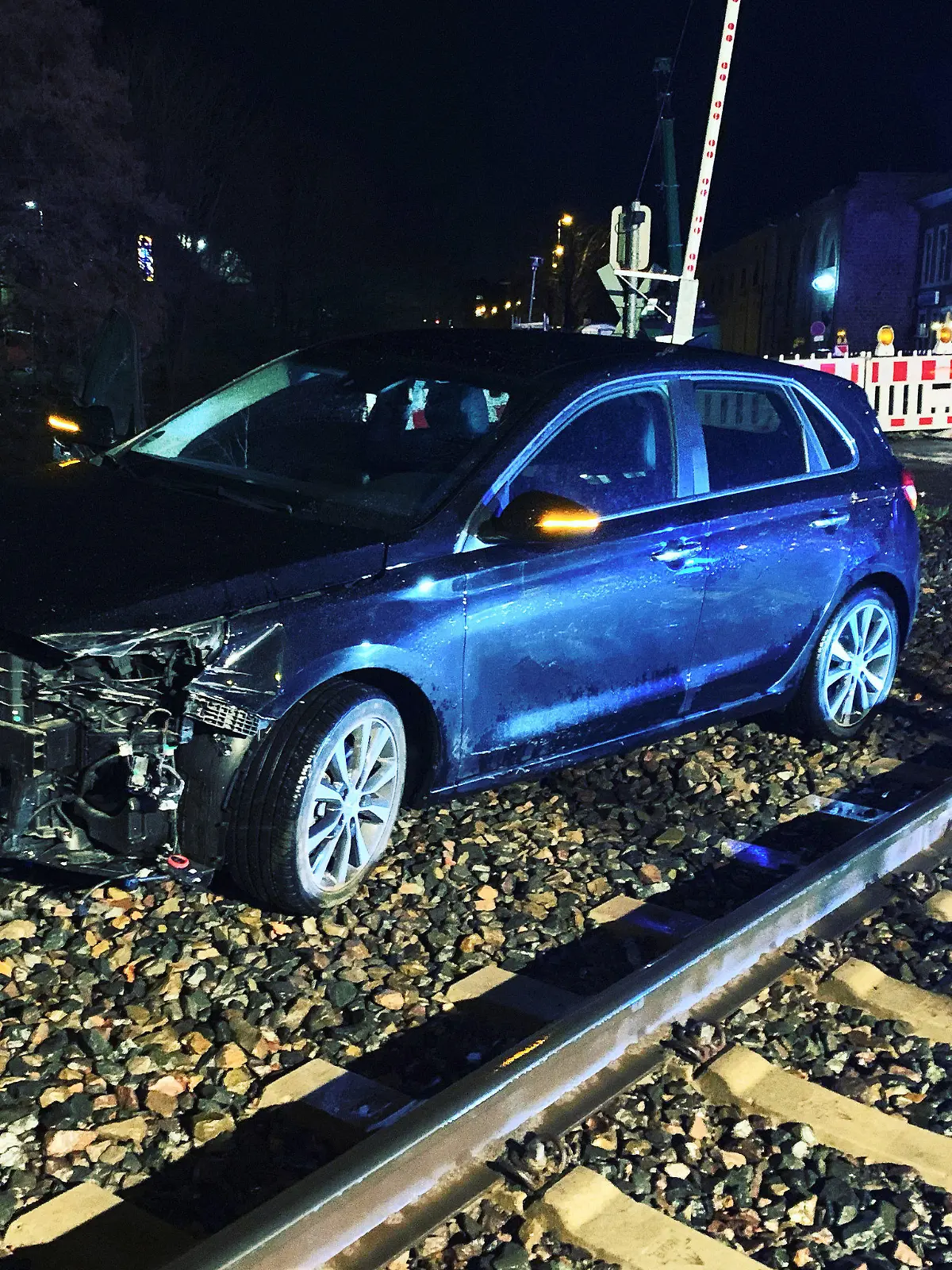 HANDOUT - 14.01.2023, Nordrhein-Westfalen, Stolberg: Ein demoliertes Auto steht neben den Schienen. Bei einem Zusammenstoß eines Autos mit einem Zug sind in Stolberg zwei Menschen verletzt worden. Eine Euregiobahn war am Samstagabend an einem Bahnübergang mit dem Pkw zusammengestoßen. Foto: -/ Feuerwehr Stolberg/dpa +++ dpa-Bildfunk +++