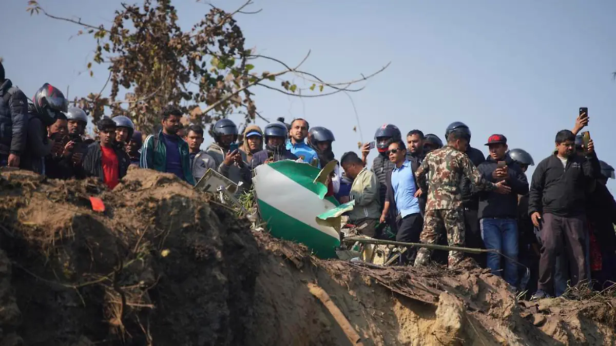 15.01.2023, Nepal, Pokhara: Einheimische schauen auf das Wrack eines abgestürzten Passagierflugzeugs und die Rettungskräfte bei den Bergungsarbeiten. Das Passagierflugzeug mit 72 Menschen an Bord ist in der Nähe des internationalen Flughafens Pokhara in Nepal abgestürzt, berichtet die Tageszeitung Kathmandu Post. An Bord des Flugzeugs befanden sich 68 Passagiere und vier Besatzungsmitglieder. Foto: Yunish Gurung/AP/dpa +++ dpa-Bildfunk +++