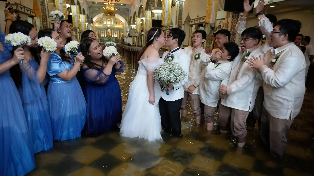 22.07.2025, Philippinen, Malolos: Die frisch Vermählten Jade Rick Verdillo und Jamaica küssen sich während ihrer Hochzeit in der überfluteten Barasoain-Kirche.