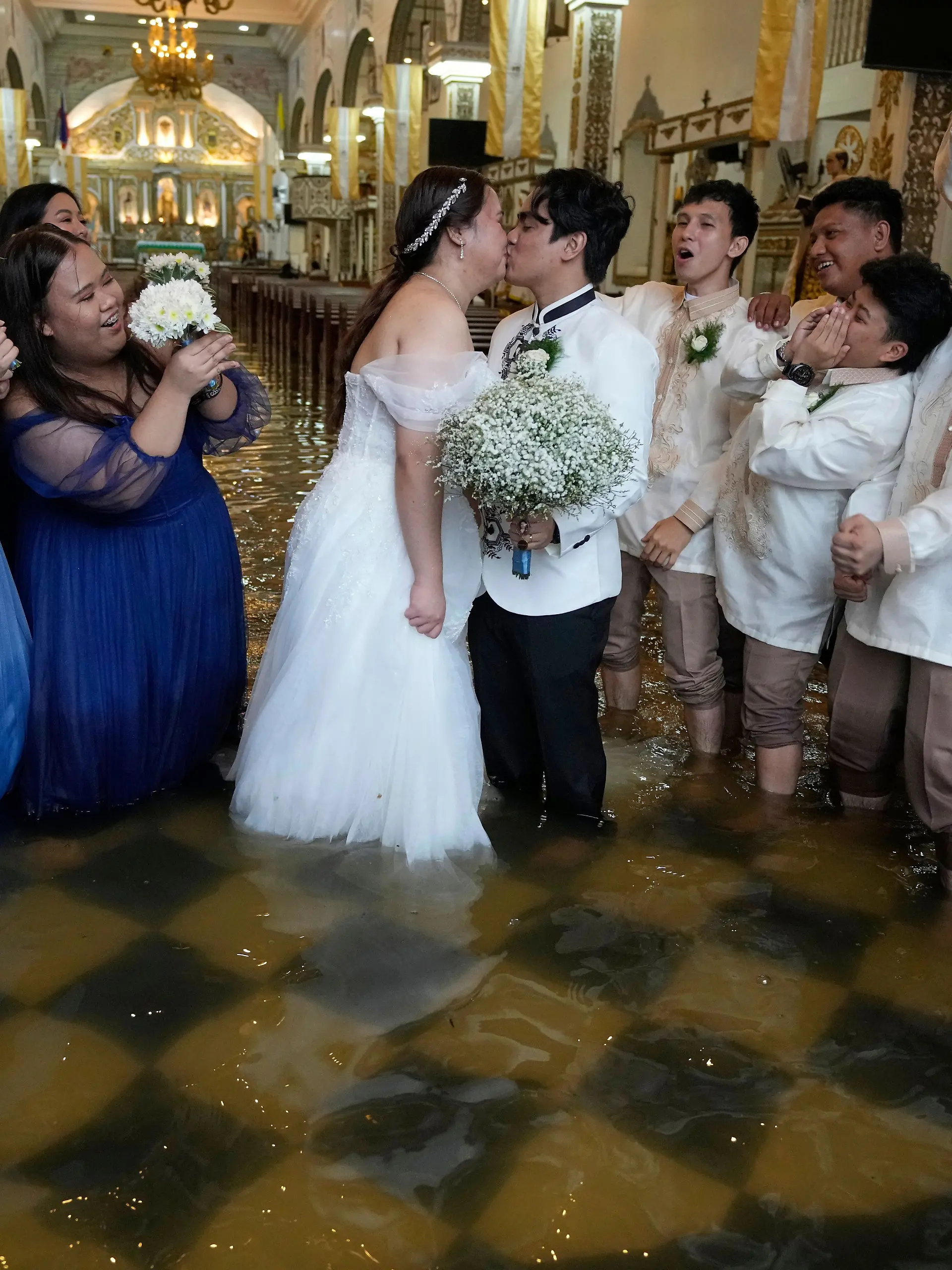 22.07.2025, Philippinen, Malolos: Die frisch Vermählten Jade Rick Verdillo und Jamaica küssen sich während ihrer Hochzeit in der überfluteten Barasoain-Kirche. 