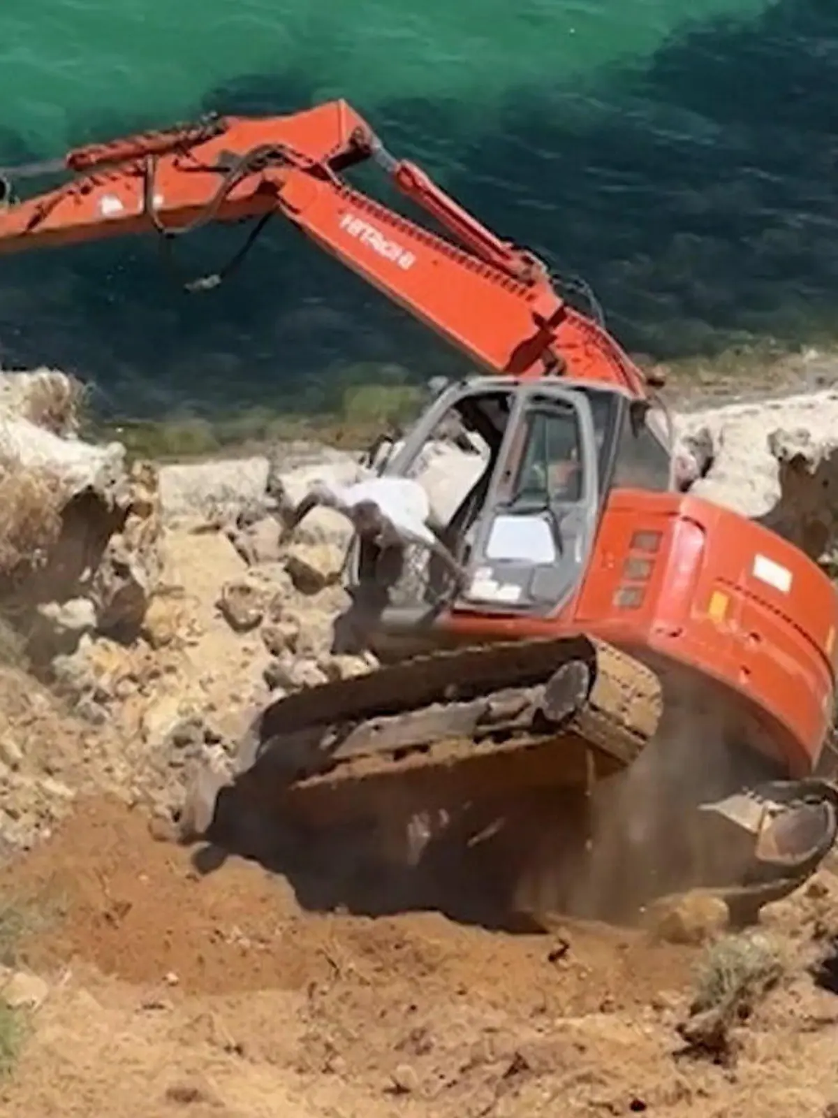 Bild zu: "Bagger kippt von Küstenhang – während Arbeiter im Führerhaus sitzt!"