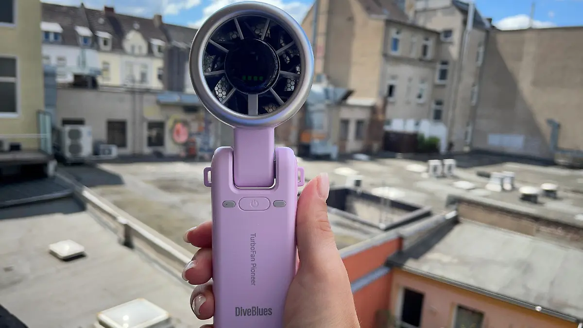 Reporterin hält lilanen Handventilator in die Luft. 