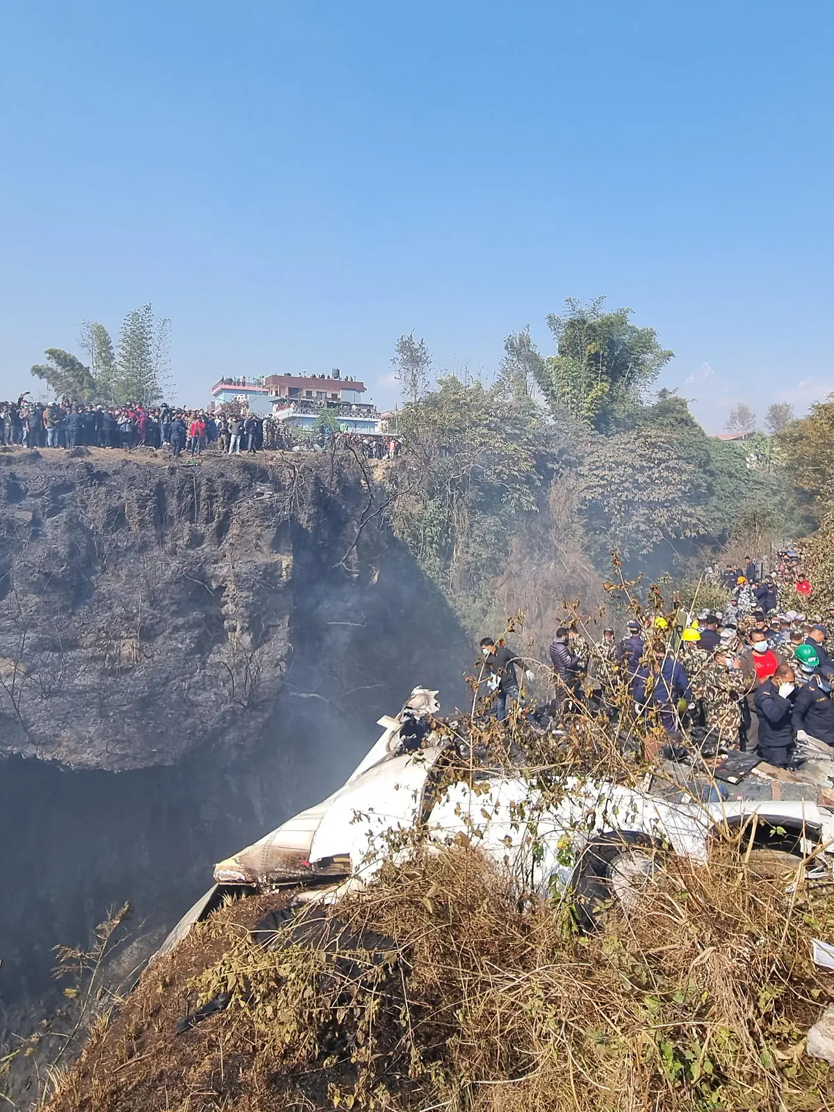Crowds gather as rescue teams work to retrieve bodies at the crash site of an aircraft carrying 72 people in Pokhara in western Nepal January 15, 2023. Bijay Neupane/Handout via REUTERS THIS IMAGE HAS BEEN SUPPLIED BY A THIRD PARTY. MANDATORY CREDIT. NO RESALES. NO ARCHIVES.