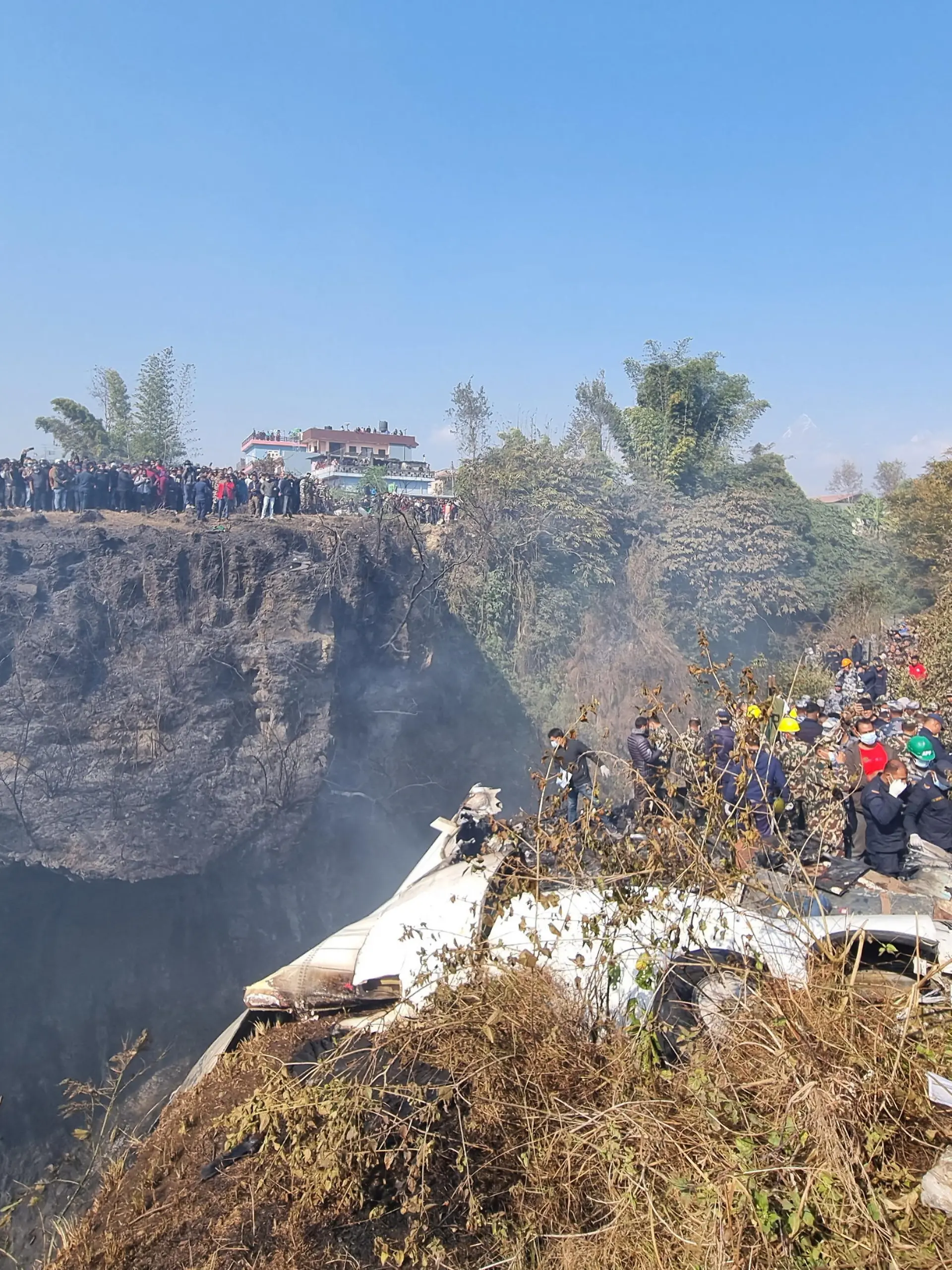 Crowds gather as rescue teams work to retrieve bodies at the crash site of an aircraft carrying 72 people in Pokhara in western Nepal January 15, 2023. Bijay Neupane/Handout via REUTERS THIS IMAGE HAS BEEN SUPPLIED BY A THIRD PARTY. MANDATORY CREDIT. NO RESALES. NO ARCHIVES.