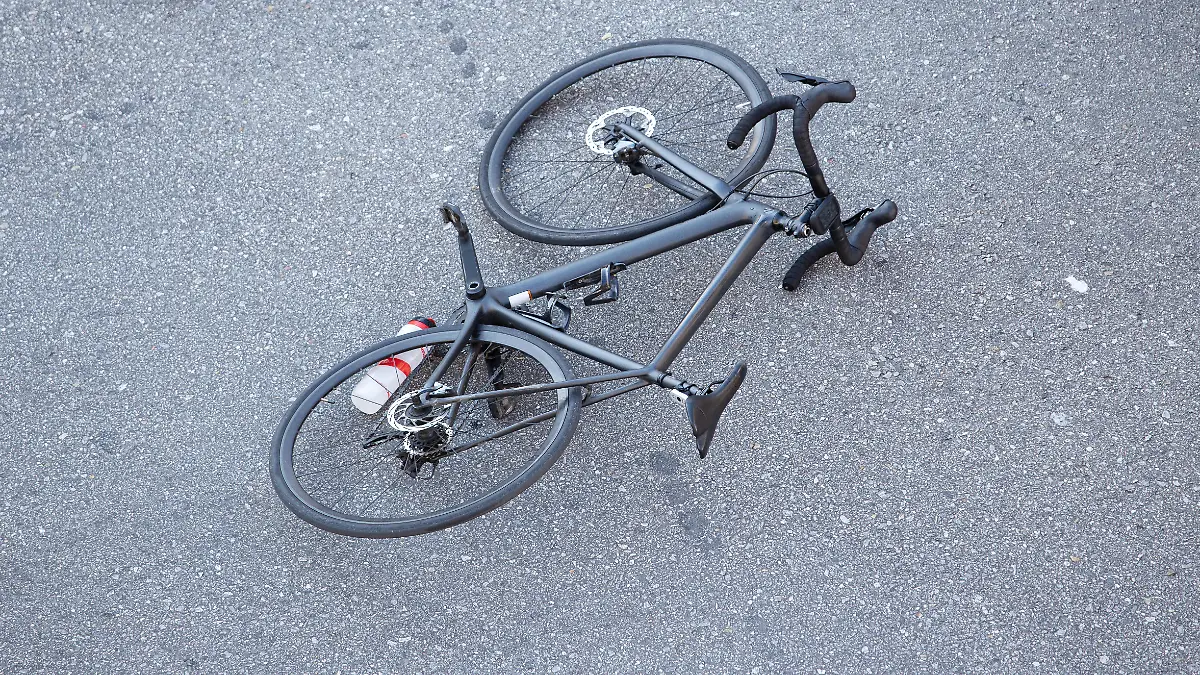 Fahrradunfall auf der Straße. Szene mit einem Radfahrer und einem Fahrrad auf dem Asphalt, nachdem sie von einem Fahrzeug angefahren wurden.