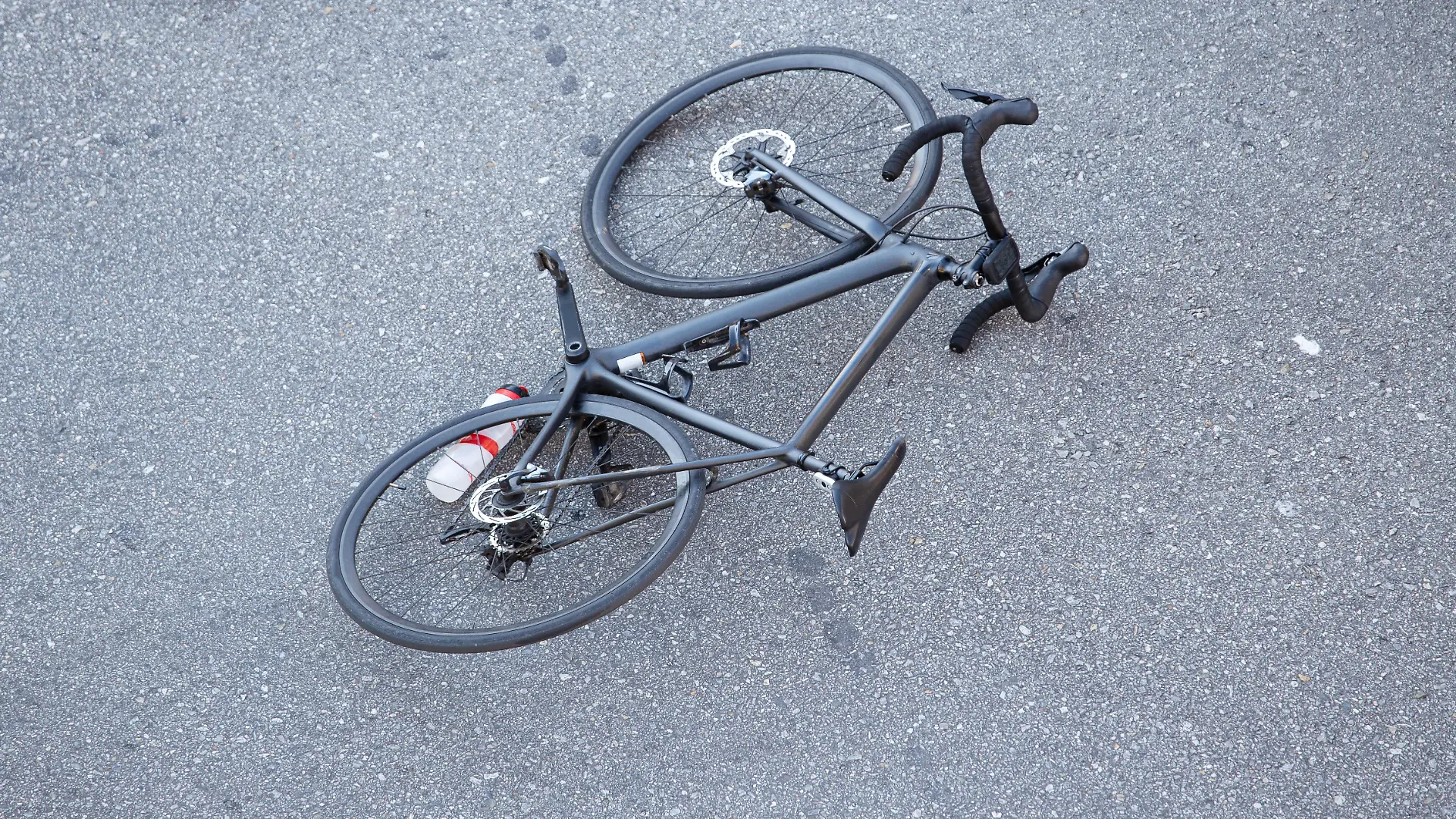 Fahrradunfall auf der Straße. Szene mit einem Radfahrer und einem Fahrrad auf dem Asphalt, nachdem sie von einem Fahrzeug angefahren wurden.