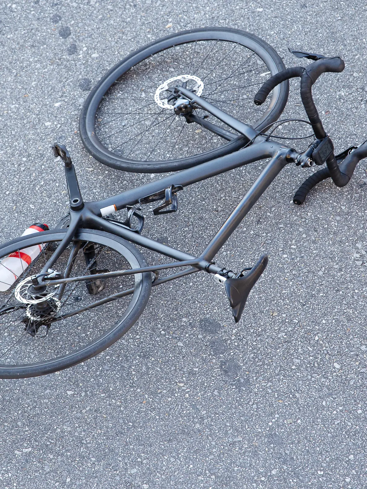 Fahrradunfall auf der Straße. Szene mit einem Radfahrer und einem Fahrrad auf dem Asphalt, nachdem sie von einem Fahrzeug angefahren wurden.