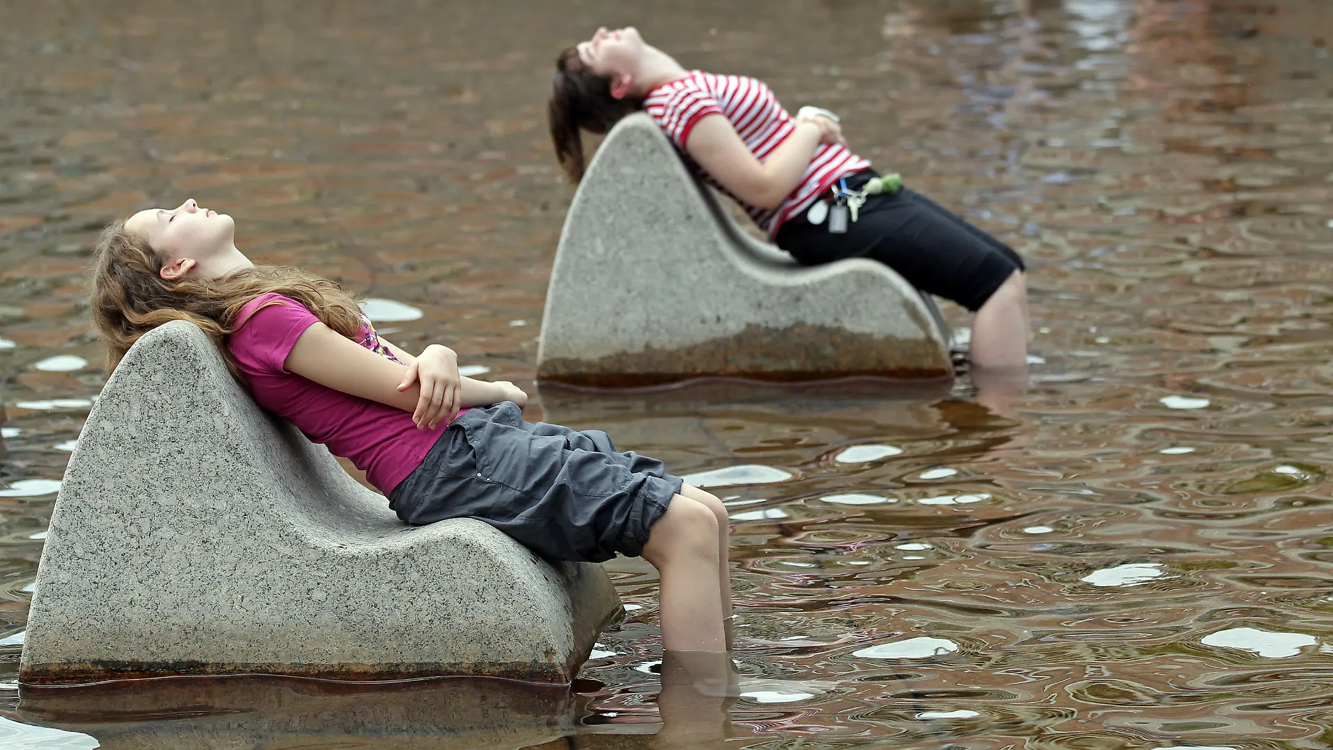 Die Schülerinnen Anne Quaas (l) und Selina Krause entspannen sich am Mittwoch (09.06.2010) in einem Springbrunnen in Chemnitz. Das Wetter soll auch in den kommenden Tagen noch sehr heiß und schwül bleiben. Foto: Jan Woitas dpa/lsn  +++(c) dpa - Bildfunk+++
