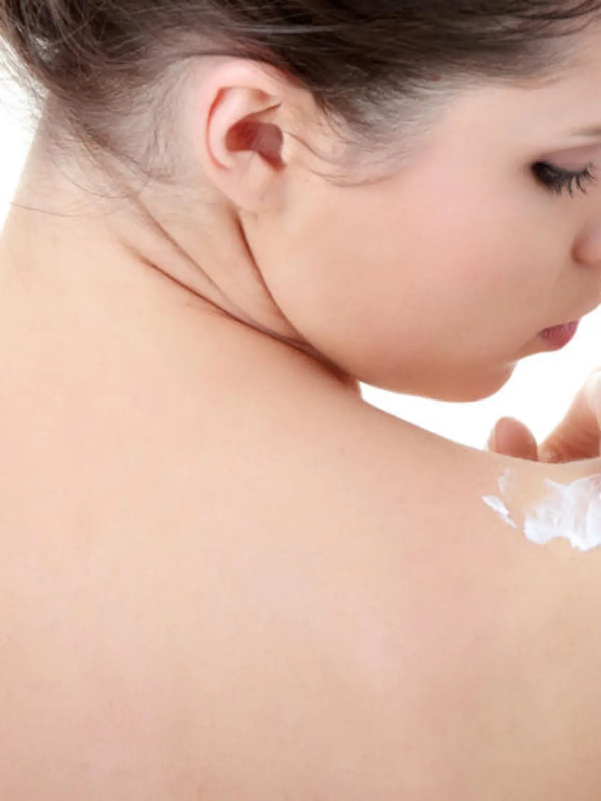 Skincare concept: back of beautiful nude woman with soft skin putting skincare product (cream) on her back