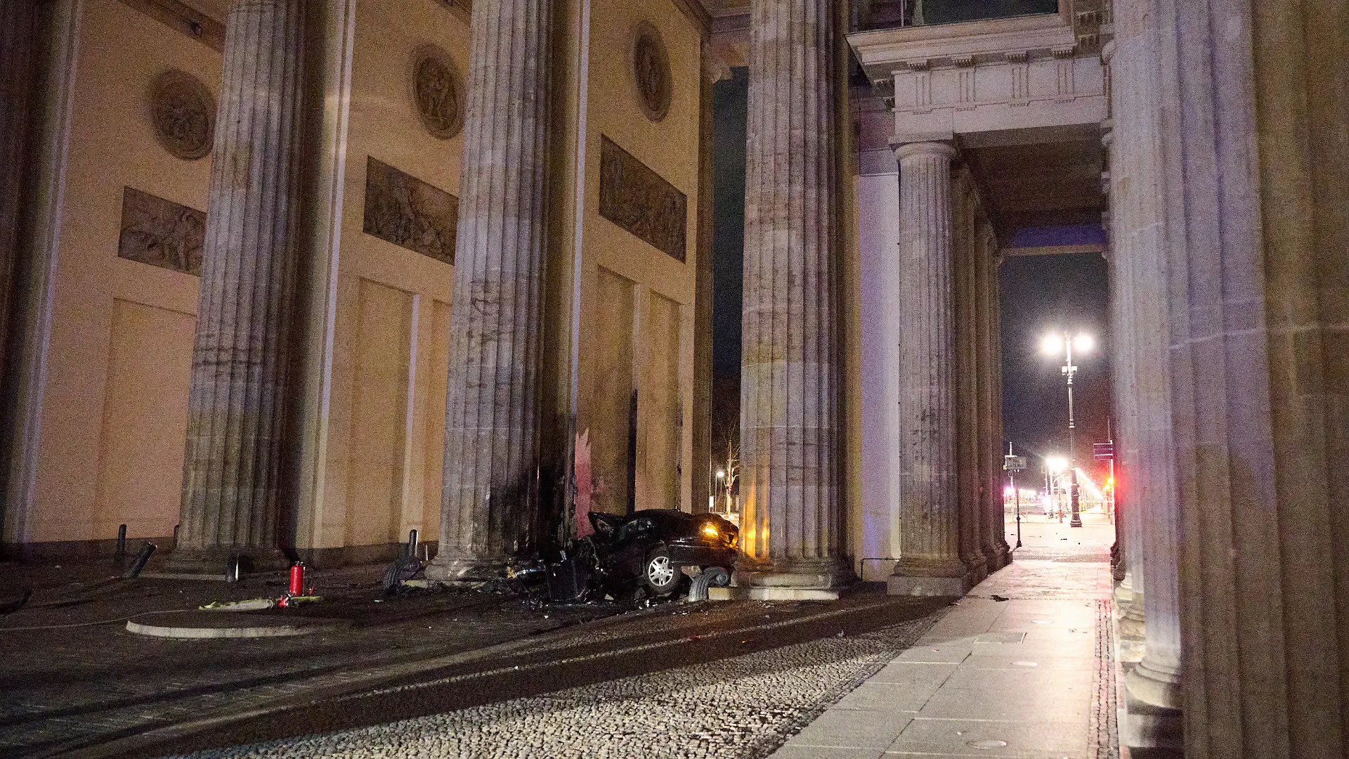 16.01.2023, Berlin: Ein zerstörter PKW liegt zwischen zwei Säulen des Brandenburger Tors. Ein Auto ist gegen eine Säule des Brandenburger Tors in Berlin gefahren. In dem Wagen hätten Feuerwehrleute einen toten Mann gefunden, sagte ein Polizeisprecher am frühen Montagmorgen. Foto: Annette Riedl/dpa +++ dpa-Bildfunk +++