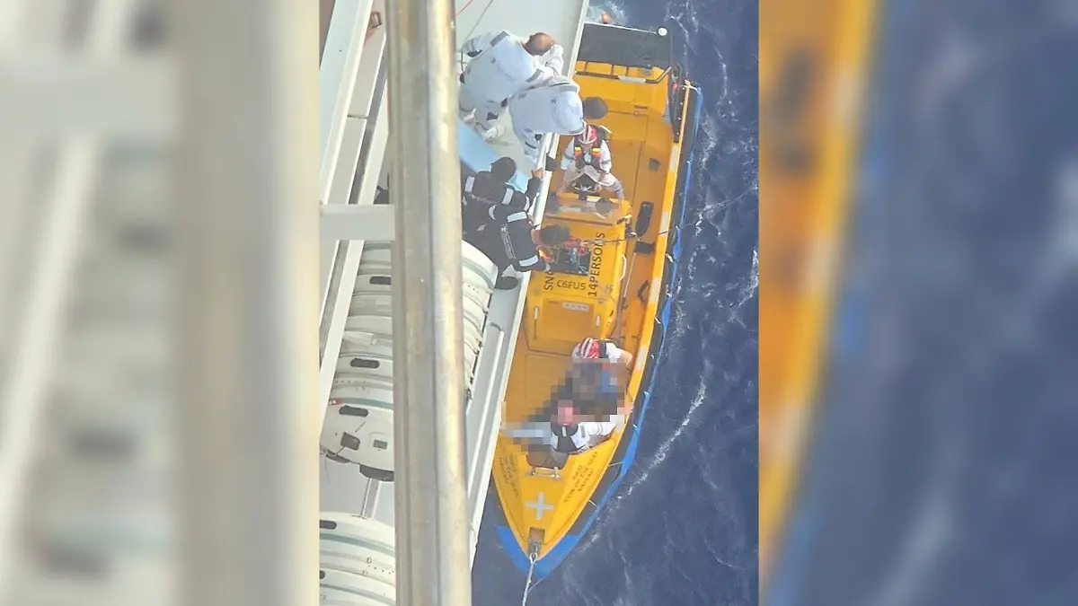 Helfer bergen das Crewmitglied aus dem Wasser.