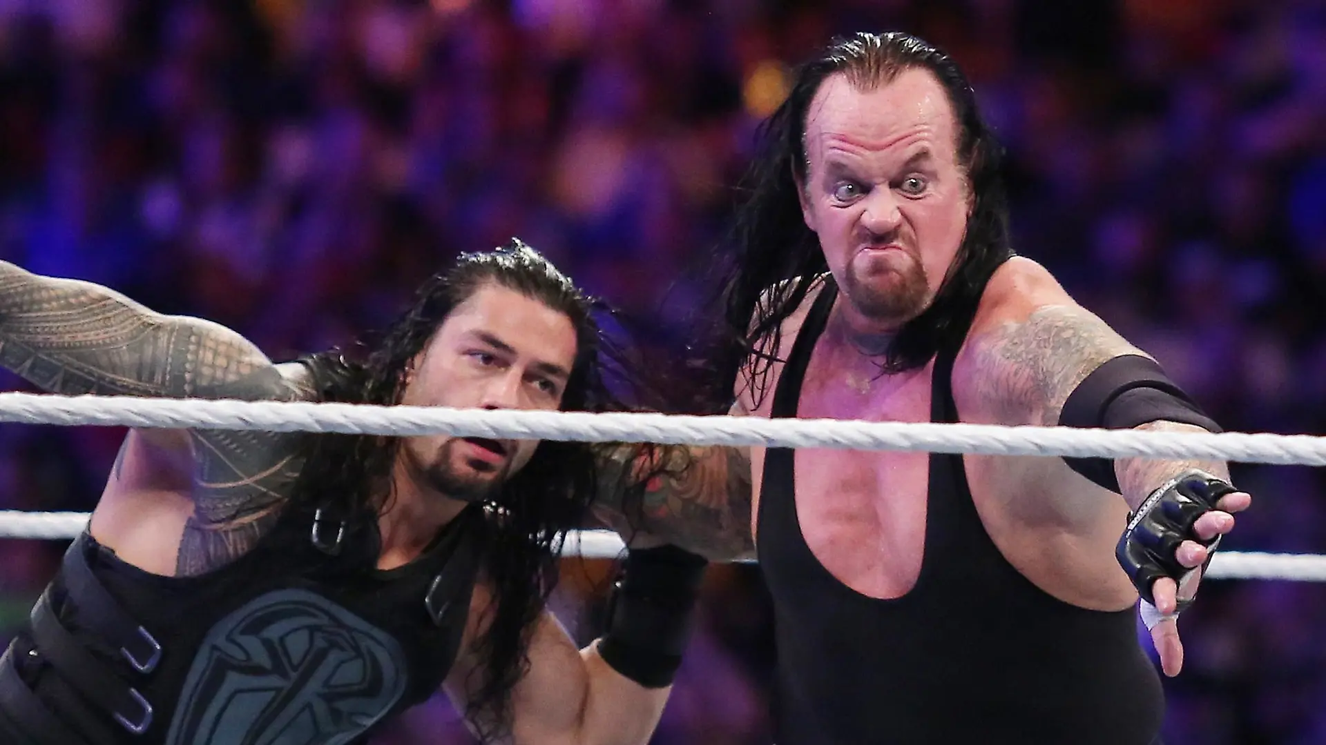 The Undertaker (rechts) mitten im Kampf. Hier schmeißt er Roman Reigns durch den Ring.