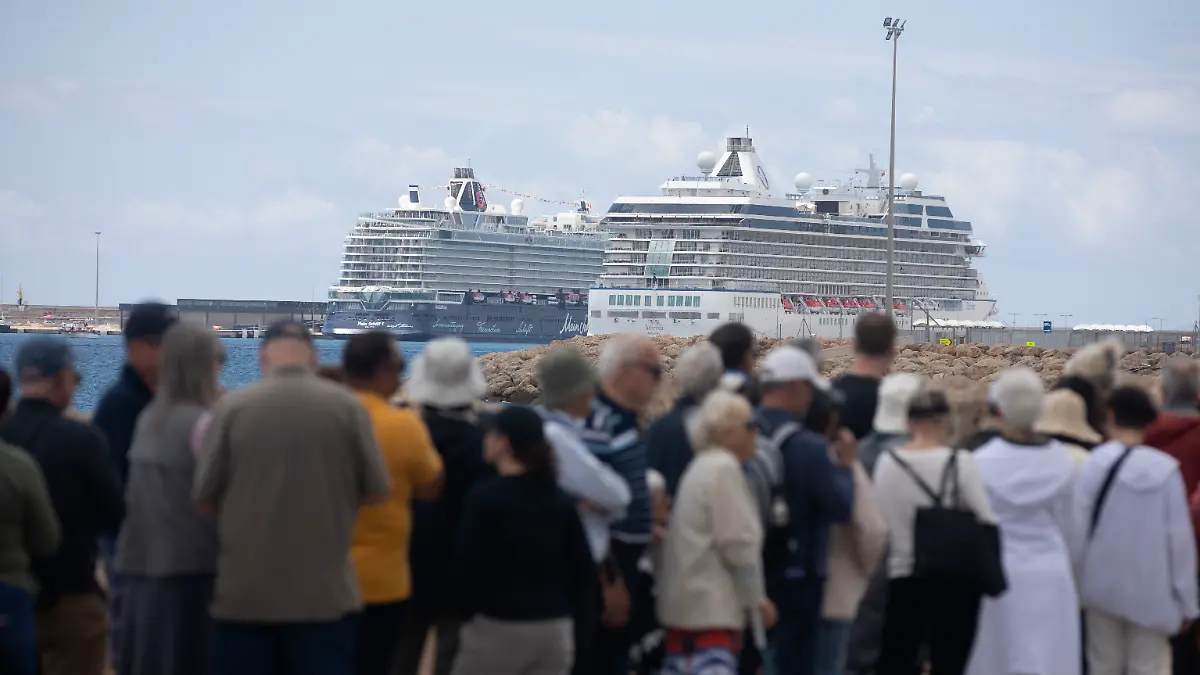 Menschen stehen im Hafen von Palma, wo einige Kreuzfahrtschiffe vor Anker liegen.