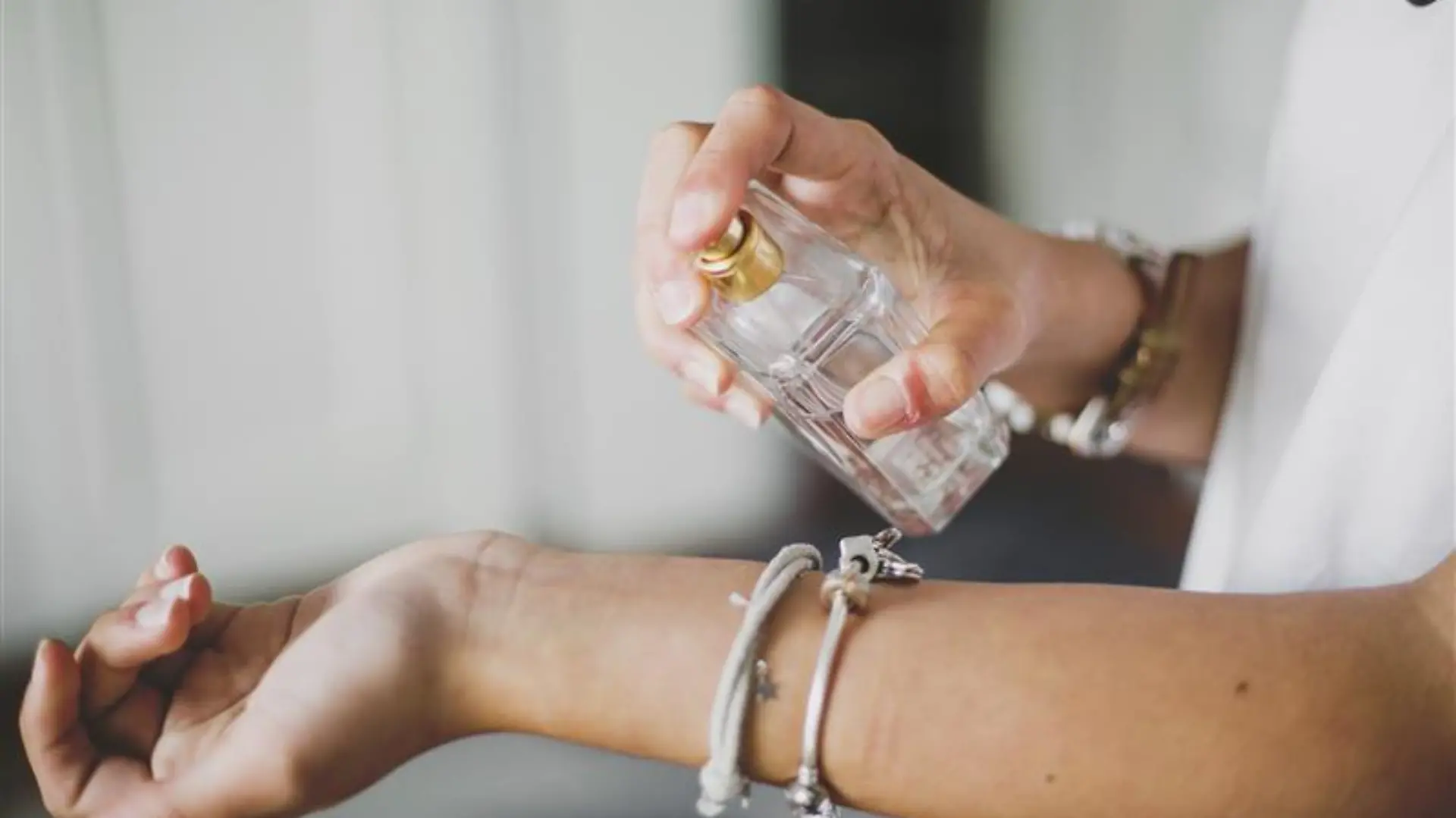 Frau trägt Apfelparfum auf das Hangelenk auf.