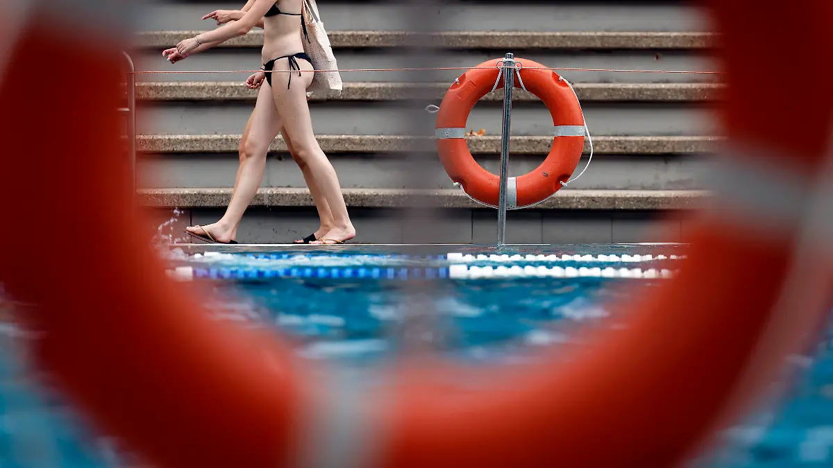 Frauen laufen in einem Freibad am Becken vorbei. 