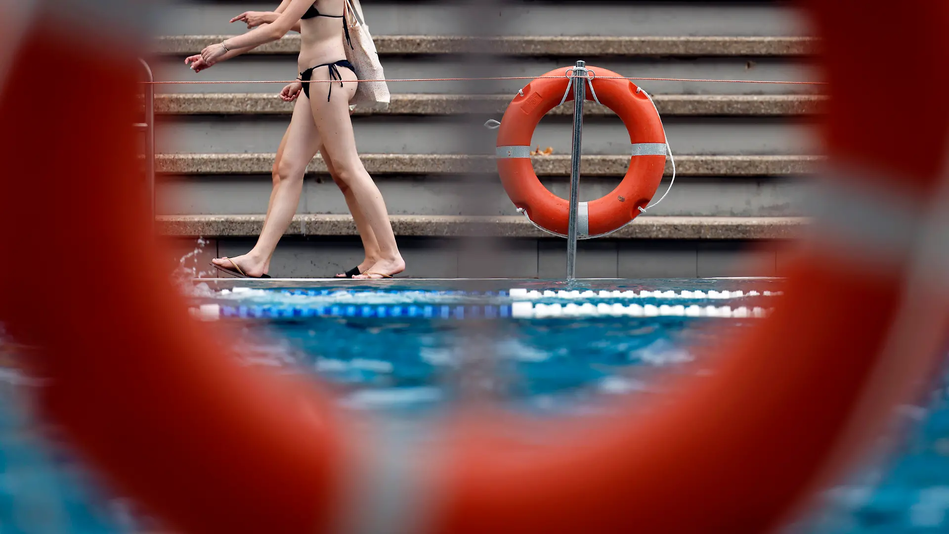 Frauen laufen in einem Freibad am Becken vorbei.