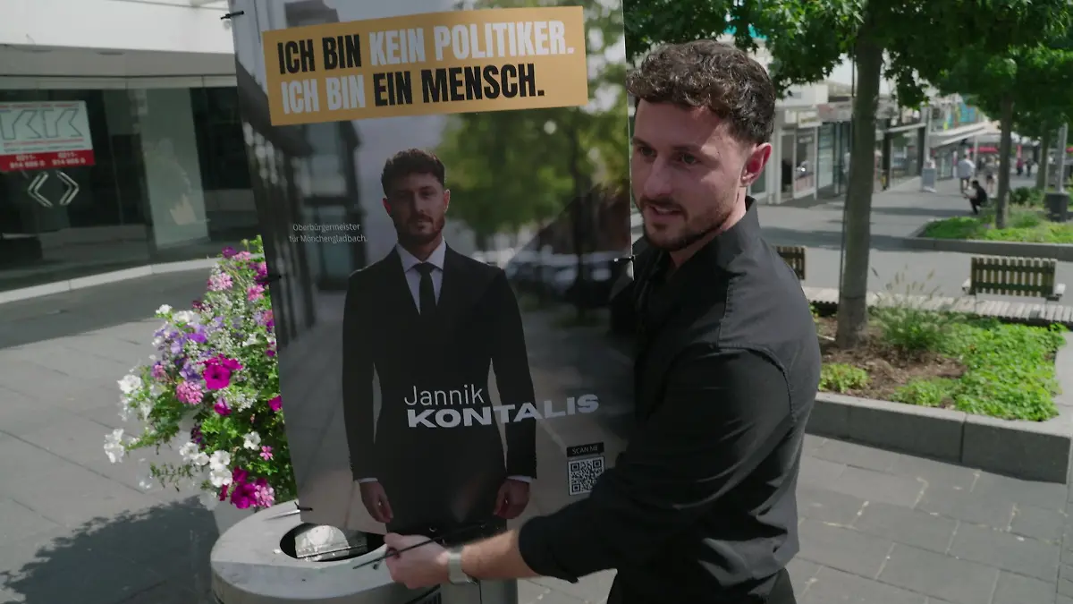 Jannik Kontalis hängt ein Wahlplakat auf.