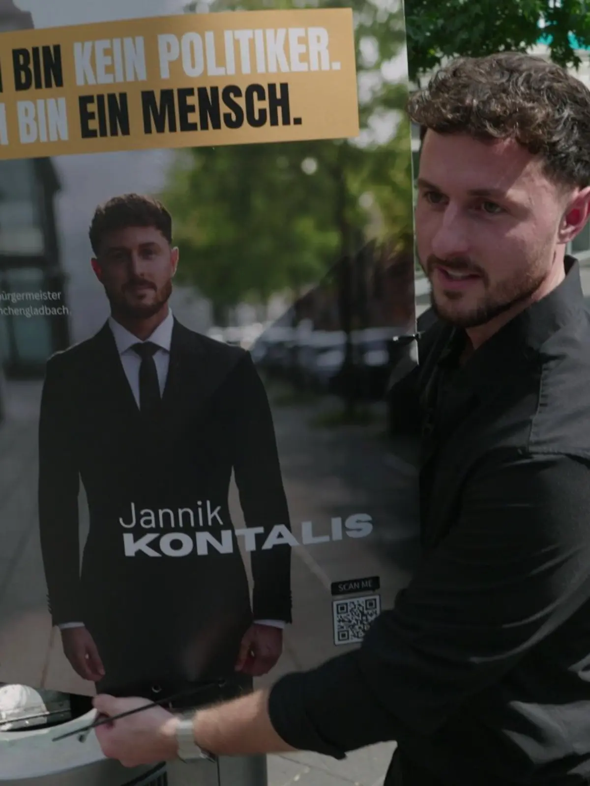 Jannik Kontalis hängt ein Wahlplakat auf.